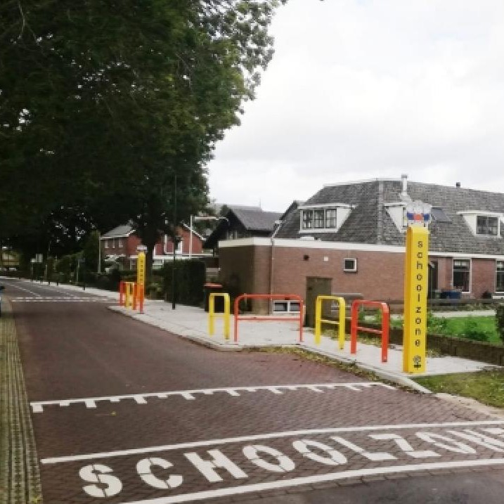 Schoolzone Dick Bruna van nijntje met verkeerspaal ook wel attentiepaal of verkeerszuil genoemd met daarop Joep poppetje boven aan de paal ook zien we hekjes in het rood, oranje en geel om te voorkomen dat kinderen zo maar oversteken. paal bedankt geel