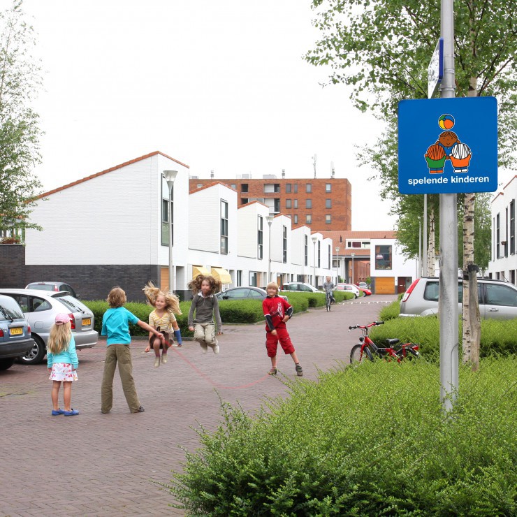 Woonerf met spelende kinderen en verkeersbord van Dick bruna bekend van nijntje dat automobilisten waarschuwt dat er kinderen op straat spelen en dus zorgt voor verkeersveiligheid op de weg voor kleine kinderen