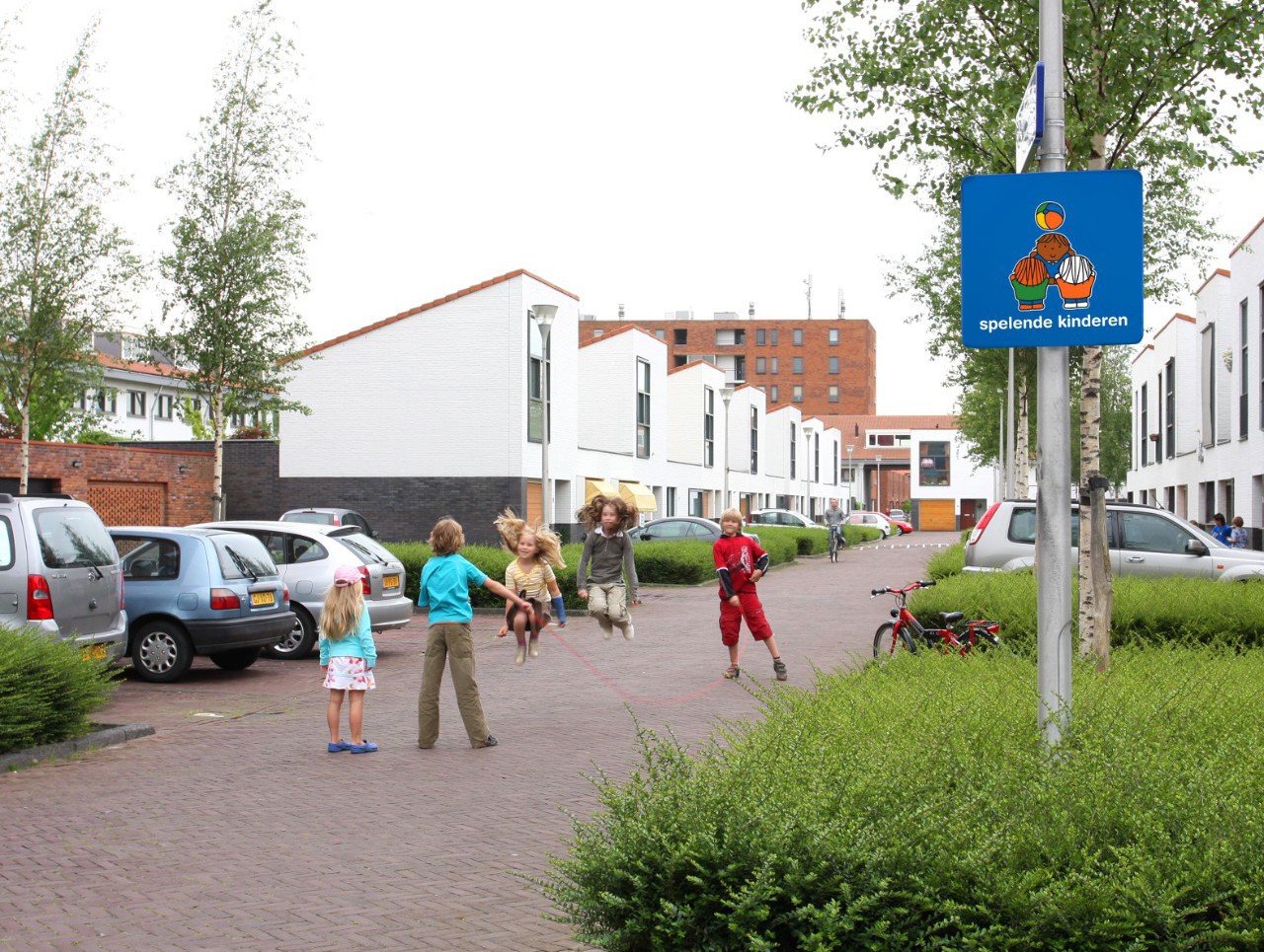 Een verkeersveilige woonomgeving en schoolomgeving met verkeersborden voor jonge kinderen die oversteken en automobilisten die opletten en bewust zijn van spelende kinderen.